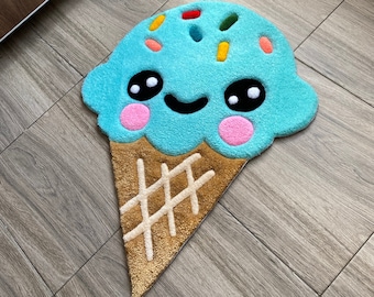 Puede incluir: Una alfombra de cono de helado azul con una cara sonriente y coloridos espolvoreos. La alfombra está hecha de un material suave y mullido y es perfecta para agregar un toque divertido a cualquier habitación.