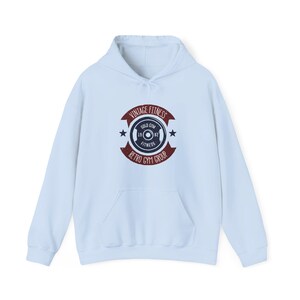 Puede incluir: Sudadera con capucha azul claro con bolsillo delantero y cordón. El diseño frontal incluye el texto "VINTAGE FITNESS" y "RETRO GYM GROUP" alrededor de un diseño de pesa.