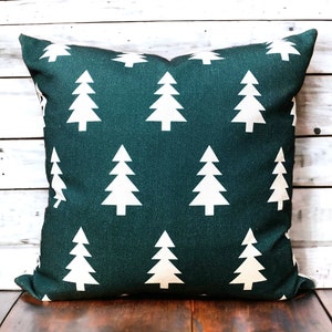 May include: A dark green throw pillow with a white repeating pattern of stylized Christmas trees.