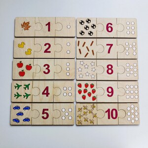 May include: Wooden puzzle pieces with numbers 1 through 10, each with a corresponding image. The images include a leaf, a duck, an apple, an airplane, a car, a soccer ball, a stick, a star, a strawberry, and a bee.