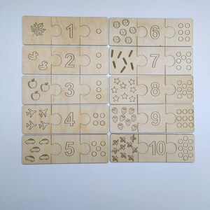May include: Wooden puzzle pieces with numbers 1 through 10, each piece has a corresponding number of images, such as leaves, ducks, apples, airplanes, cars, soccer balls, pencils, stars, strawberries, and bees.