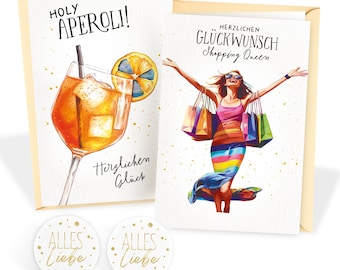 May include: Two greeting cards and two small round stickers. One card says "Holy Aperoli!" with a watercolor illustration of a cocktail. The other card says "Herzlichen Glückwunsch Shopping Queen" with a woman holding shopping bags. The stickers say "Alles Liebe".