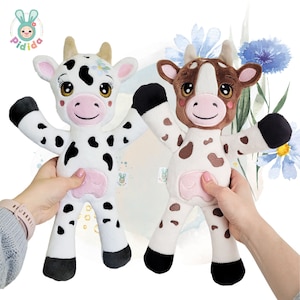 May include: Two plush cow toys with black and white spots. One cow is white with black spots and the other is brown with white spots. Both cows have pink noses and black eyes.