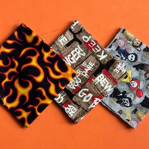 May include: Three square bandanas with distinct patterns. One displays yellow and orange flames on a black backdrop. Another has a wooden sign design with the words "ENTER IF YOU DARE" and "KEEP OUT". The third features horror movie characters.