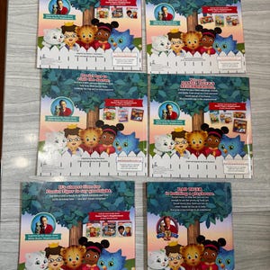 K&ouml;nnte beinhalten: Sechs Kinderb&uuml;cher mit Daniel Tiger-Charakteren. Jedes Buchcover zeigt ein Cartoon-Bild von Daniel Tiger und seinen Freunden, mit Text wie "Daniel freut sich auf die &Uuml;bernachtung" und "Daniel Tigers Nachbarschaft."