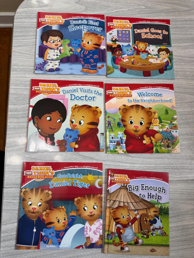 K&ouml;nnte beinhalten: Sechs Kinderb&uuml;cher aus der Reihe "Daniel Tiger's Neighborhood" werden gezeigt. Die Cover zeigen Illustrationen von Daniel Tiger und anderen Charakteren in verschiedenen Umgebungen, mit Titeln wie "Daniel's First Sleepover" und "Big Enough to Help."