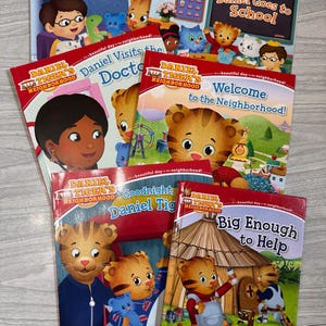 K&ouml;nnte beinhalten: Eine Sammlung von Kinderb&uuml;chern mit der Figur Daniel Tiger. Zu den Titeln geh&ouml;ren "Daniel's First Sleepover", "Daniel Goes to School", "Daniel Visits the Doctor" und "Welcome to the Neighborhood!". Die B&uuml;cher haben rote Einb&auml;nde.