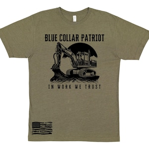 Puede incluir: Camiseta verde oliva con un gráfico negro de una excavadora y el texto "BLUE COLLAR PATRIOT" arriba e "IN WORK WE TRUST" abajo. Un gráfico de la bandera estadounidense está en la parte inferior izquierda.