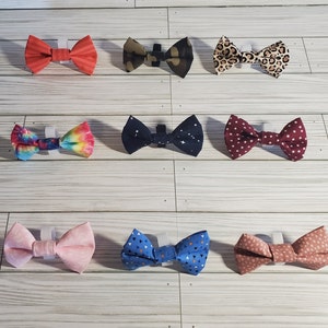 May include: Assortment of ten bow ties in various colors and patterns, including red, blue, green, pink, and black. The bow ties are made of fabric and have a white background.