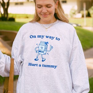 May include: A gray sweatshirt with a blue graphic of a milk carton with a face and the text "On my way to hurt a tummy".