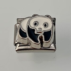 Puede incluir: Un charm de pulsera de plata con un panda blanco y negro.