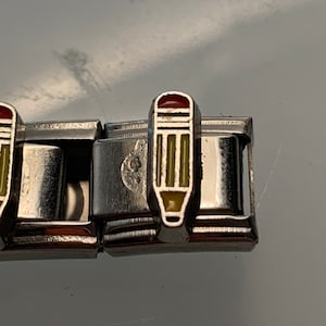 Op de afbeelding: Een zilveren armband met een potloodbedel. De potloodbedel is geel, groen en rood.