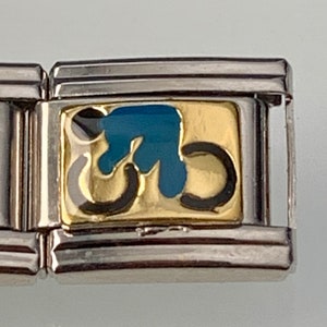May include: A silver charm bracelet with a gold and blue charm featuring a stylized bicycle design.