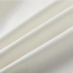 K&ouml;nnte beinhalten: Nahaufnahme eines cremefarbenen Stoffes mit diagonalen Falten. Der Stoff hat eine subtile Textur und scheint ein mittelschweres Material zu sein. Die Falten erzeugen Schatten und Lichtreflexe und verleihen dem Bild Tiefe. Die Farbe des Stoffes ist ein weiches, cremiges Wei&szlig;.