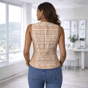 K&ouml;nnte beinhalten: Ein beiges &auml;rmelloses Oberteil mit einem wei&szlig;en geometrischen Muster auf dem R&uuml;cken. Das Oberteil wird mit einer blauen Jeans kombiniert. Das Muster zeigt Rauten und Linien. Das Oberteil ist neutralfarben und scheint aus einem glatten Stoff zu sein.