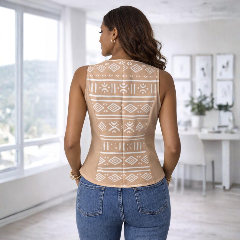 K&ouml;nnte beinhalten: Ein beiges &auml;rmelloses Oberteil mit einem wei&szlig;en geometrischen Muster auf dem R&uuml;cken. Das Oberteil wird mit einer blauen Jeans kombiniert. Das Muster zeigt Rauten und Linien. Das Oberteil ist neutralfarben und scheint aus einem glatten Stoff zu sein.