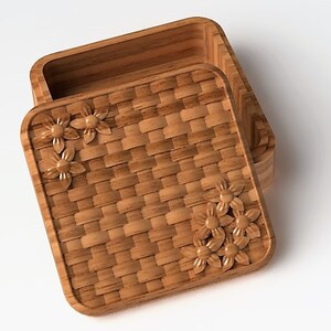 May include: A wooden box with a woven lid. The lid has a floral design carved into it.