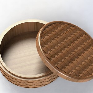 May include: A round wooden box with a lid. The lid has a woven pattern and the box is open.