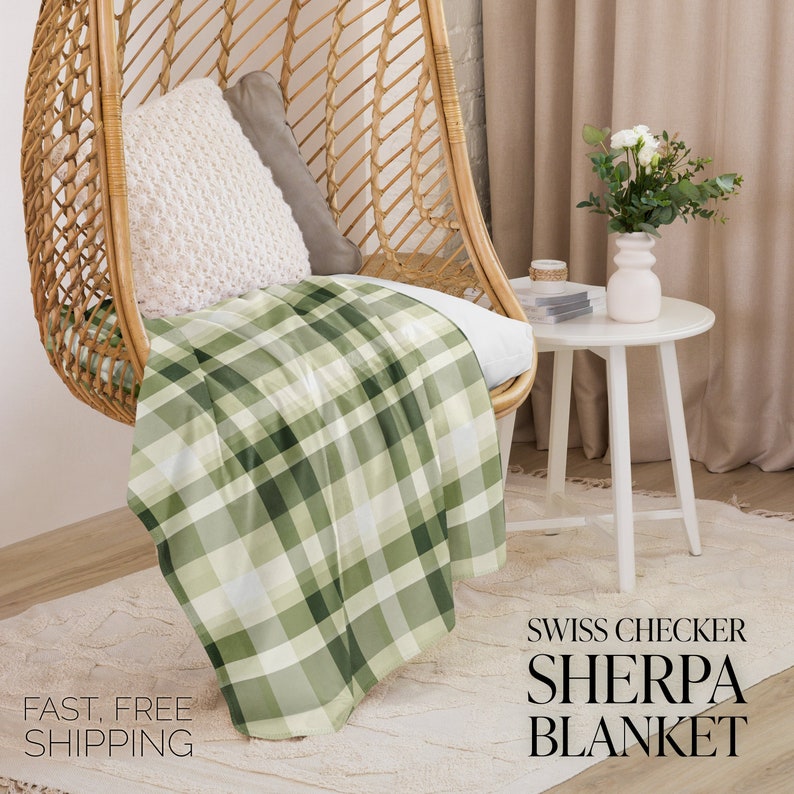 May include: A green and white plaid sherpa blanket draped over a wicker chair. The blanket has a "Swiss Checker Sherpa Blanket" text label.