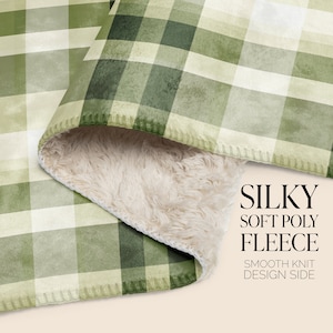 May include: A green and white plaid fleece blanket with a soft, fluffy white sherpa lining. The blanket is folded in half, showing both sides. The text "SILKY SOFT POLY FLEECE" and "SMOOTH KNIT DESIGN SIDE" is printed on the blanket.