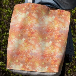 May include: A tote bag with a fall-themed design featuring orange, yellow, and red leaves on a white background with a subtle shimmer effect.