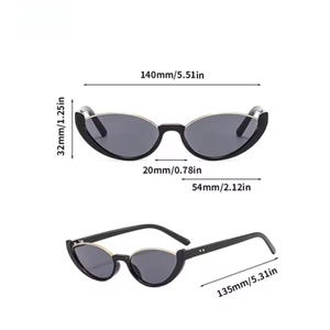K&ouml;nnte beinhalten: Schwarze Cat-Eye-Sonnenbrille mit silberfarbenen R&auml;ndern und dunklen Gl&auml;sern. Angegebene Ma&szlig;e: 140 mm Gesamtbreite, 32 mm Glash&ouml;he, 20 mm Stegbreite, 54 mm Glasbreite und 135 mm B&uuml;gell&auml;nge. Dargestellt in einer Frontal- und einer Schr&auml;gansicht.