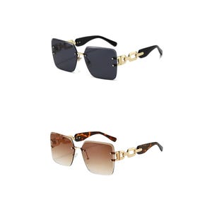 May include: Two pairs of rimless sunglasses. One pair has dark gray lenses, black arms, and gold chain-link accents. The other pair has brown gradient lenses, tortoise shell arms, and gold chain-link accents. Both have square frames.