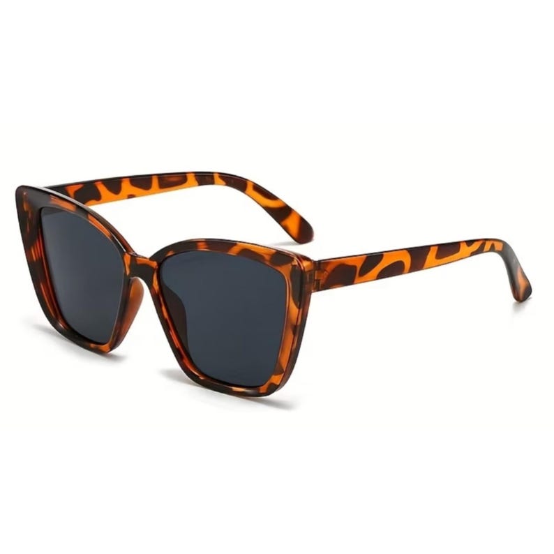 Pu&ograve; includere: Occhiali da sole a occhi di gatto con montatura a fantasia tartarugata e lenti scure. Gli occhiali da sole hanno un design classico ed elegante, adatto a varie forme di viso. La montatura presenta un motivo maculato marrone e nero.