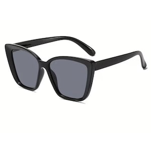 Pu&ograve; includere: Occhiali da sole neri a occhi di gatto con lenti grigio scuro. Gli occhiali hanno una montatura nera spessa e lucida e una forma angolare classica. Le lenti sono di un grigio scuro uniforme, offrendo un look elegante. Un accessorio alla moda.