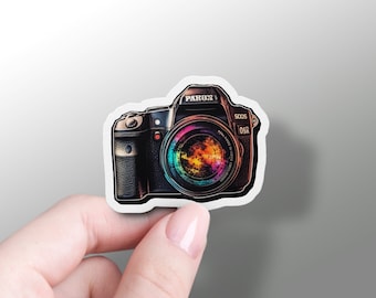 May include: A sticker of a black and brown camera with a colorful lens. The camera has the text "PAROX 1" and "500S" on it.