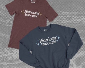 May include: Two shirts with the text "Historically Inaccurate" printed on them. One shirt is a maroon t-shirt with gold stars and the other is a navy blue sweatshirt with light blue stars.