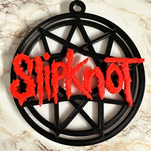 May include: A black and red 3D printed ornament featuring the band name "Slipknot" in red lettering inside a black pentagram.