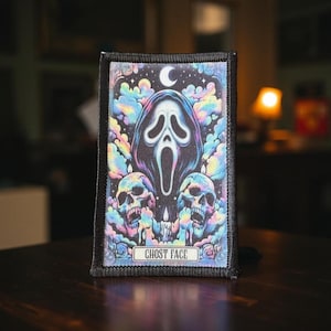 May include: A rectangular patch featuring a Ghost Face design. The design includes a white mask, two skulls, a crescent moon, and colorful clouds. The text "GHOST FACE" is at the bottom.