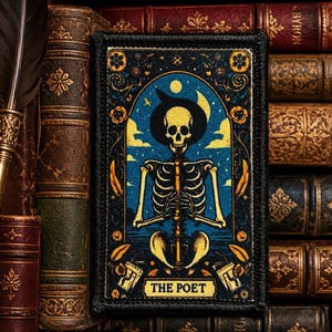 May include: A rectangular embroidered patch featuring a skeleton wearing a wide-brimmed hat against a blue night sky with a crescent moon and stars. The design is framed by yellow floral motifs and includes the text THE POET at the bottom.