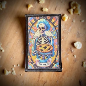 May include: A rectangular patch featuring a skeleton baker holding a pie. The skeleton wears a blue bonnet and apron, set against a stained-glass style background with the text "THE BAKER" at the bottom. The patch has a black border.