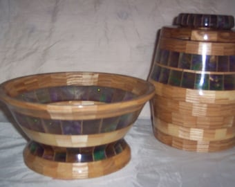 Op de afbeelding: Een houten kom en een houten pot met deksel, beide met een mozaïekpatroon van hout en iriserend materiaal.
