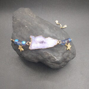 May include: A purple agate slice bracelet with gold star charms and iridescent blue beads.