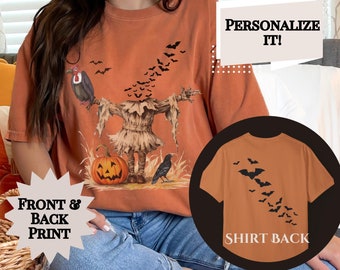 Könnte beinhalten: Orangefarbenes T-Shirt mit Halloween-Motiv. Die Vorderseite zeigt eine Vogelscheuche, einen Kürbis und eine Krähe, mit Fledermäusen darüber. Die Rückseite zeigt einen Schwarm Fledermäuse. Auf dem T-Shirt steht "Personalize It!" und "Front & Back Print".