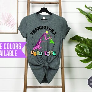 May include: A heather dark grey t-shirt with a graphic of a pink praying mantis eating a green leaf. The text "Thanks for a Good Time" is written in a retro font around the mantis.