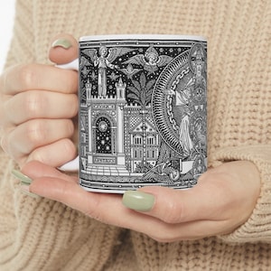 May include: White ceramic mug featuring a black and white illustration of a church and figures. The illustration is detailed and includes the word "APHTHRUS".