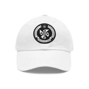Peut inclure: Casquette de baseball blanche avec un patch circulaire noir et blanc représentant une croix et le texte "LAUDARE, PRAEDICARE, BENEDICERE".