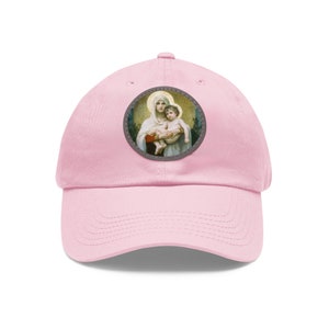 Peut inclure: Casquette de baseball rose avec un patch rond représentant une peinture de la Vierge Marie tenant un bébé Jésus.