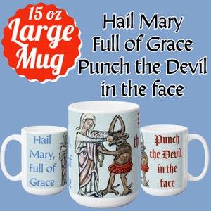 May include: White ceramic mug with a 15 ounce capacity. The mug features a colorful illustration of the Virgin Mary punching the devil in the face. The text "Hail Mary, Full of Grace" is printed on the left side of the mug. The text "Punch the Devil in the face" is printed on the right side of the mug.