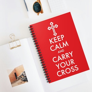 May include: A red spiral notebook with a white cross and the text "Keep Calm and Carry Your Cross".