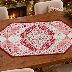 May include: A hexagonal fabric table runner featuring a patchwork design with red and green holiday-themed patterns, including snowflakes, pine trees, and ornaments, finished with a solid red border and intricate quilted stitching.