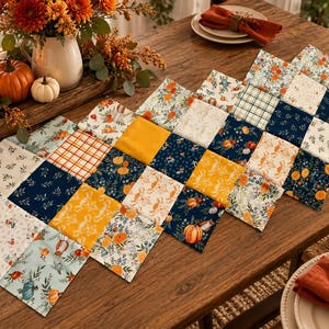 May include: A patchwork table runner featuring a repeating grid of square fabric panels. The design includes alternating patterns of navy blue, mustard yellow, and white, decorated with illustrations of pumpkins, autumn leaves, and plaid.