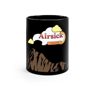 May include: Black ceramic mug with a brown mountain and a white cloud with the text "Airsick Lowlander" in orange and red.