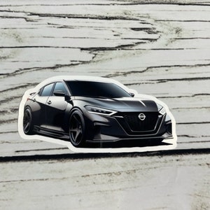 May include: A black car with a sleek design. The car has a large front grille with a chrome Nissan logo. The car is on a white wooden background.