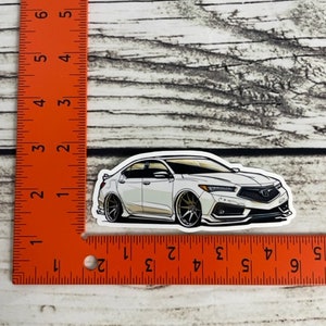 May include: White car sticker with black outlines. The car is a saloon with a sporty design. The sticker is approximately 5 cm long.