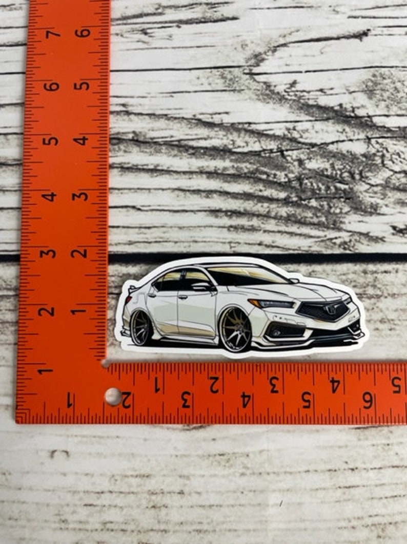 May include: White car sticker with black outlines. The car is a saloon with a sporty design. The sticker is approximately 5 cm long.